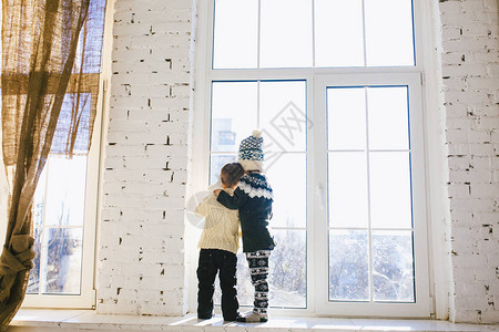 两个婴儿高加索男孩和女孩兄弟姐妹站在大盒子的窗户前图片