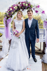 欢乐的年轻结婚夫妇在婚礼仪式上站在图片
