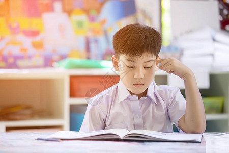 快乐的亚洲儿童阅读书和思考早晨图片