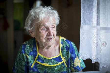 一名老年妇女坐在窗户旁边的房子图片