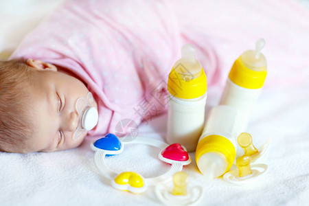 可爱的新生女婴与奶瓶拨浪鼓和奶嘴婴儿配方奶粉新出生的孩子图片