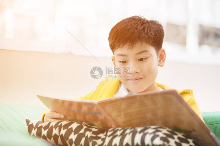 亚洲快乐男孩在沙发上读故事书清晨图片