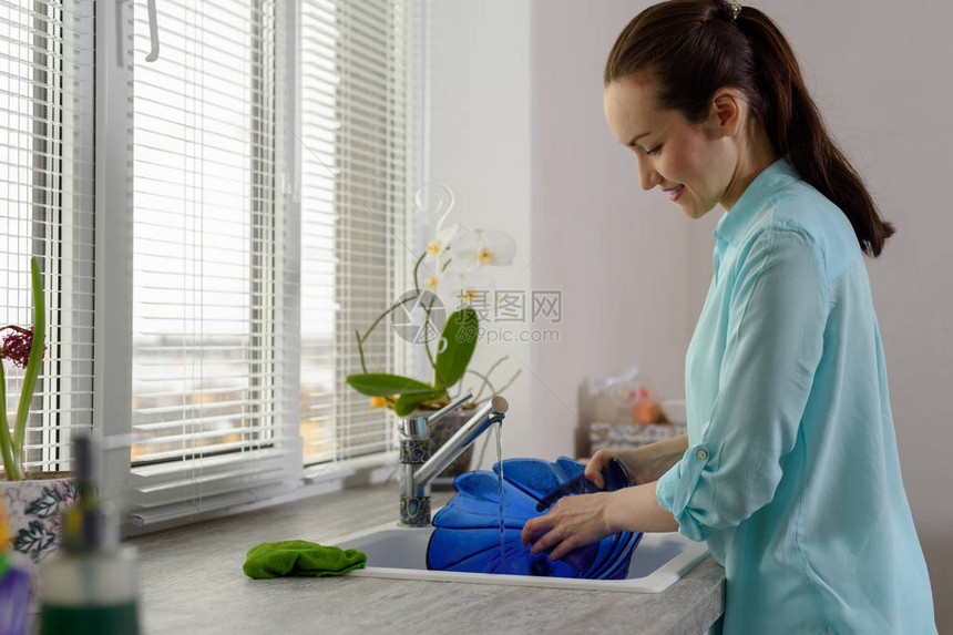 洗碗在厨房窗户前拿着蓝色盘图片