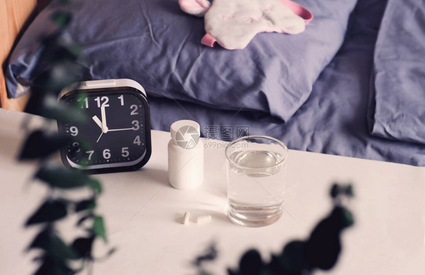 健康的睡眠概念医疗胶囊和床头柜上的一杯水褪黑激素和昼夜节律有安图片