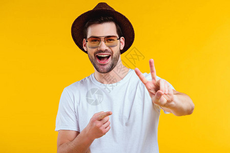 身穿白色T恤帽子和太阳镜的快乐年轻人展示胜利标志图片