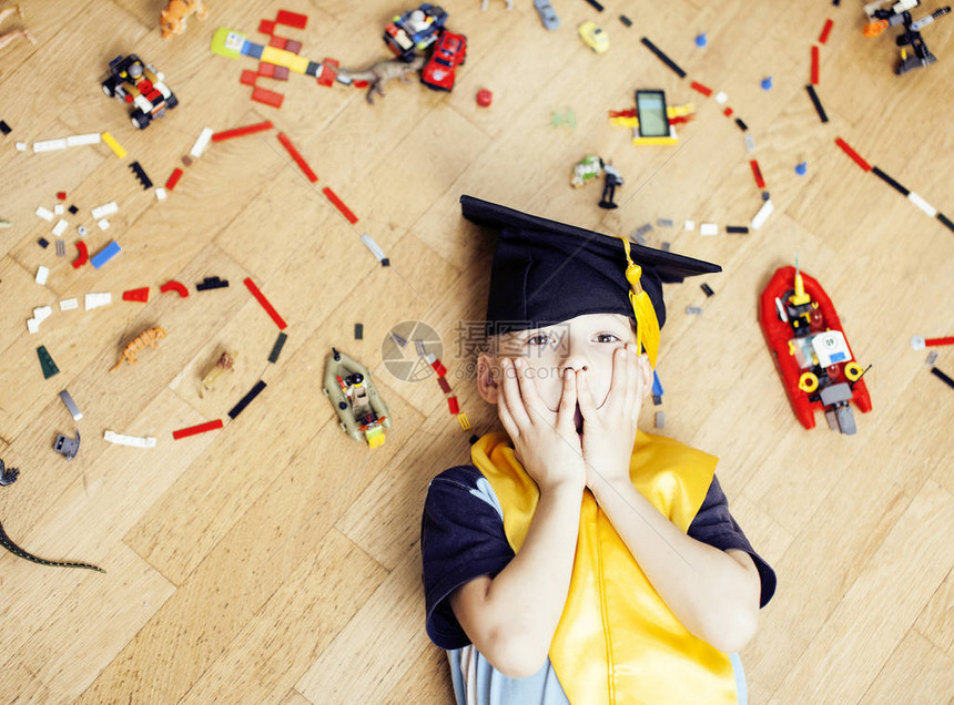家中玩具乐高玩具中的小可爱学龄前男孩戴着毕业帽微笑着摆出情绪化生活方式的人概念图片