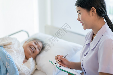 亚洲护士检查躺在床上的老年病人的病史护士照图片