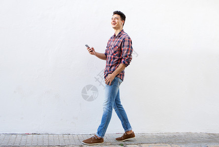 一个微笑的男人在手机上行走和听音乐的图片
