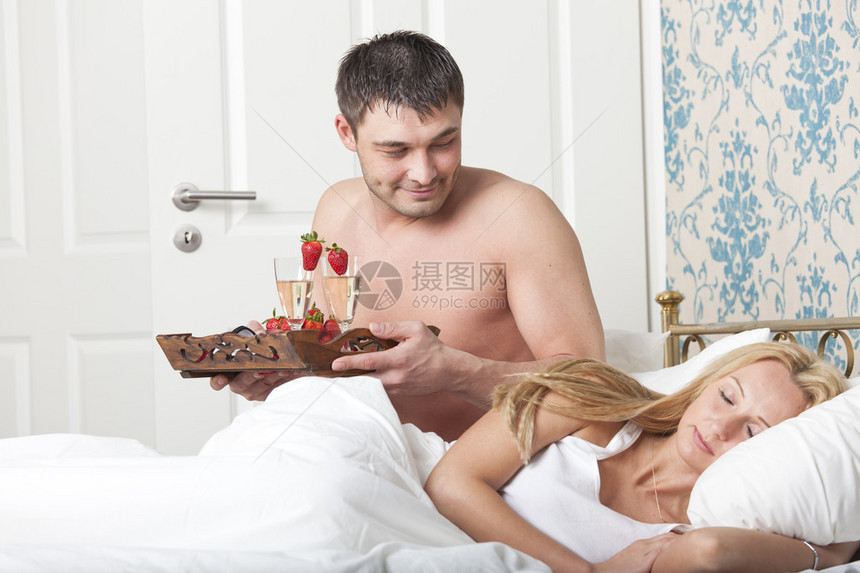 男人用两杯起泡酒送早餐上床睡觉图片