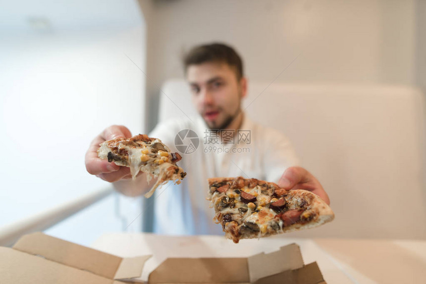 男人手里拿着两块披萨图片