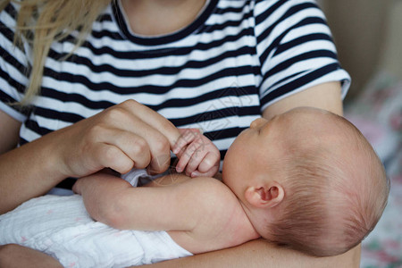 一位年轻母亲正在母乳喂养她七天大的女儿背景