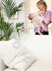 母亲和新出生的女儿在家里的客厅里放松图片