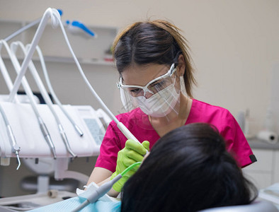 女牙医清洁病人的牙齿医生戴着口图片