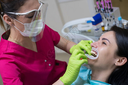 诊所牙医女病人的近视肖像牙齿白程序医生正在安装牙科切图片