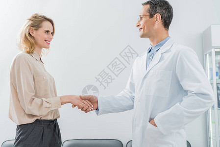 现代牙科诊所中男医生和女病人握手图片
