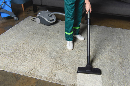 使用真空清洁和清洁白地毯进行专业清洁工的高角度图片