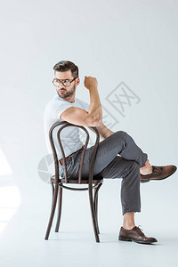 戴着眼镜坐在白背景的椅子上的图片