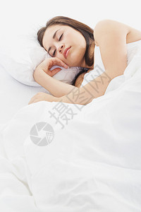 妇女睡在床上白床铺和白床上睡图片