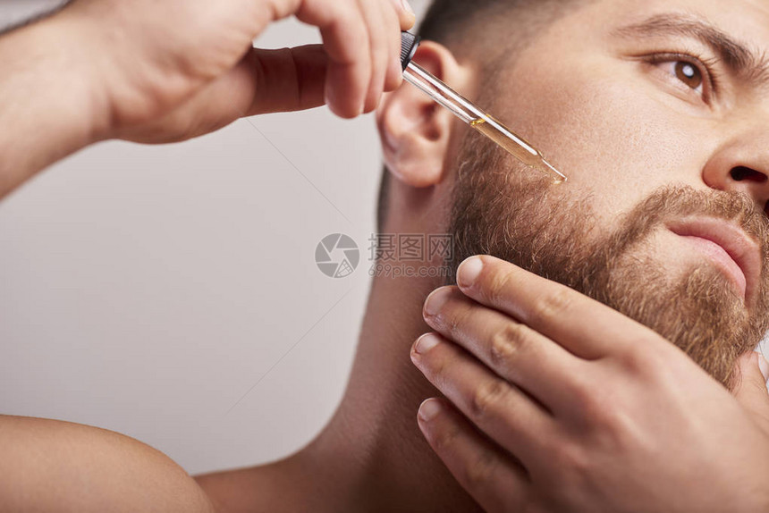 英俊男子手持吸管用油留胡子的特写图像图片