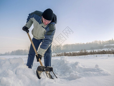 大雪后男子用铲子在后院犁地图片