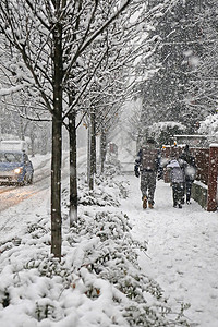 在冬天降雪期间一家人在城市人行道上散步图片