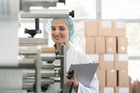 女制造主管在厂内部质量控制过程中检查设备和生产时图片