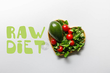 白色背景的心形碗中新鲜绿色蔬菜的顶部视图图片