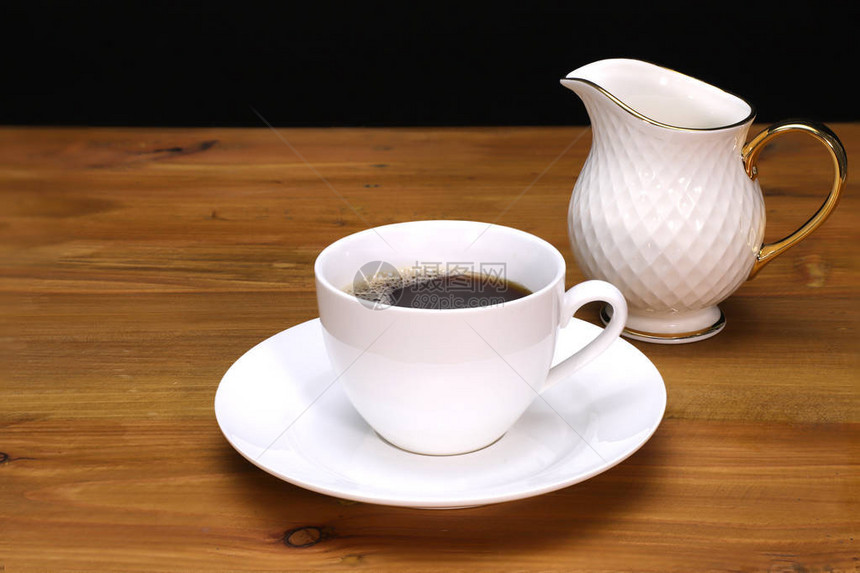 白瓷咖啡杯茶碟和奶罐在棕色木制桌顶图片