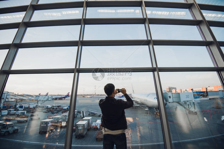 的旅行者在机场用手机为他的飞机拍照背景是空中图片