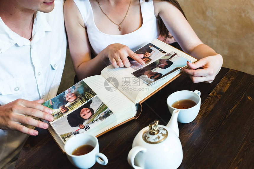 看家庭相册的年轻夫妇一个女孩指着相册中与她的男图片