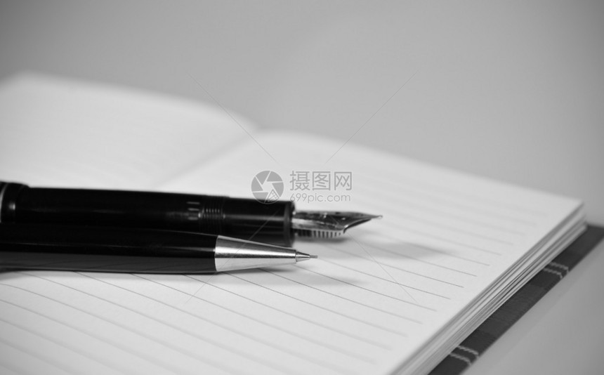 笔记本上的黑白自动铅笔和钢笔图片