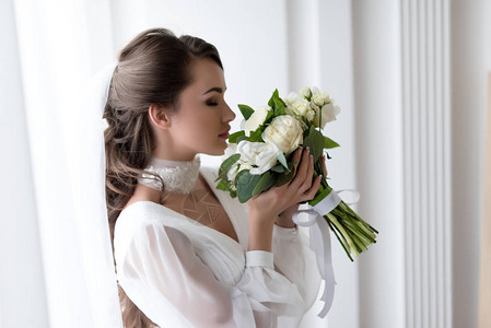 穿着婚纱和面纱闻白色花图片