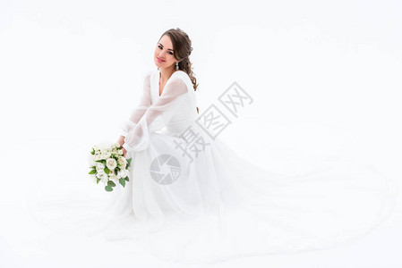 穿着优雅礼服的微笑新娘拿着婚礼花束在图片