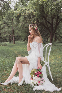 美丽沉思的年轻新娘拿着婚礼花束坐在图片