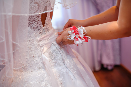 伴娘帮新娘穿上白色婚纱图片