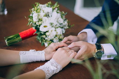 新婚夫妇在婚礼花束背景上握手图片