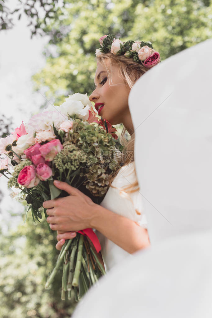 鲜花环和面纱中的年轻新娘低角度视角露天图片