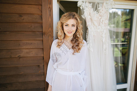 穿着白色袍的美丽年轻新娘在相机上微笑图片