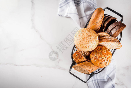 金属篮子中各种新鲜自制谷物面包图片