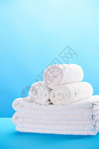 蓝色上滚动和堆叠的干净白色毛巾的特写视图图片
