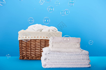 干净的白毛巾洗衣篮和蓝色的肥皂泡图片