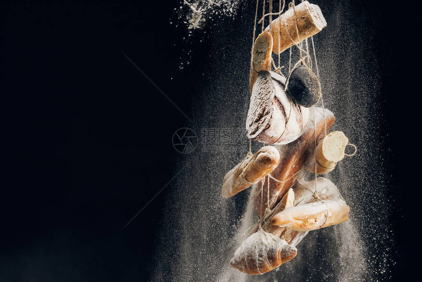 面粉白面粉倒在面包面包条和羊角面包上图片