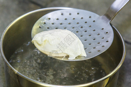 煮荷包蛋用漏勺将鸡蛋从水中捞出图片
