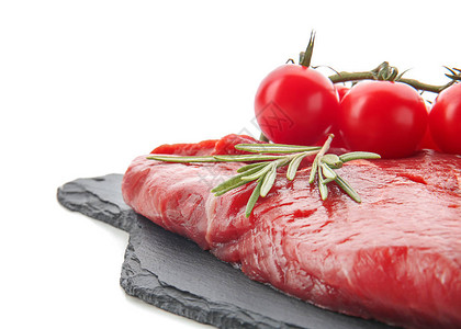白色背景中新鲜生肉迷迭香和西红柿的石板盘图片