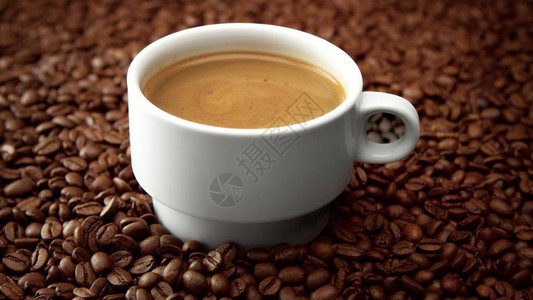 咖啡豆上黑咖啡因的白色咖啡杯一面咖啡奶油图片