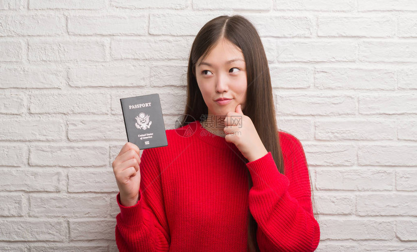 持有美国护照的年轻女子在砖墙上翻墙图片