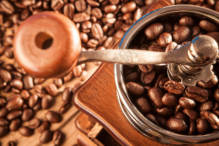 木桌上有咖啡豆的老式手动咖啡研磨机图片