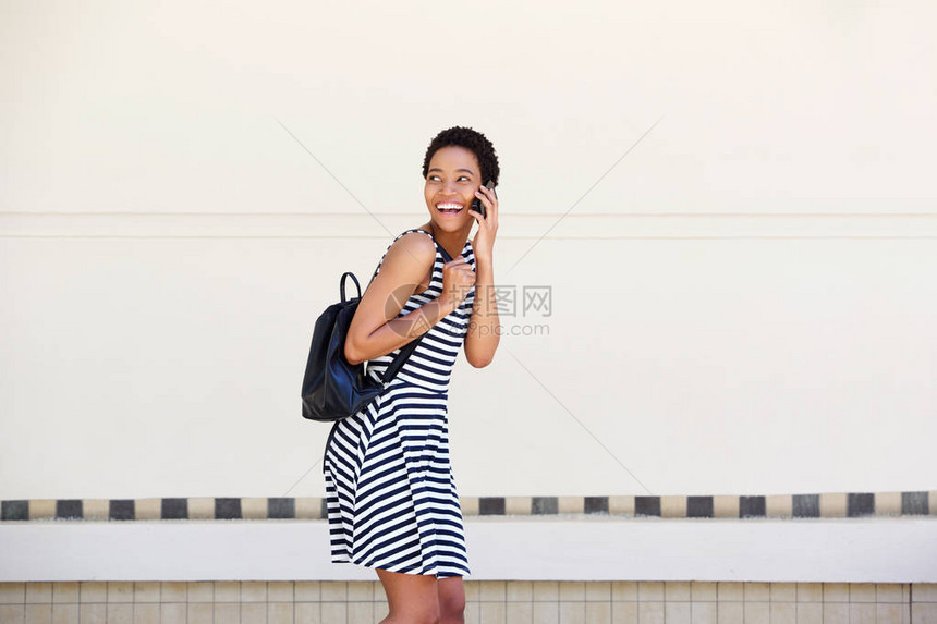 笑的年轻女子走路和用手机说图片