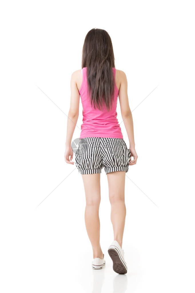 年轻的亚洲女人在后视线下行走在白色背图片