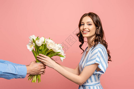 男人展示一束白色郁金香的花束给被粉红色隔离的图片